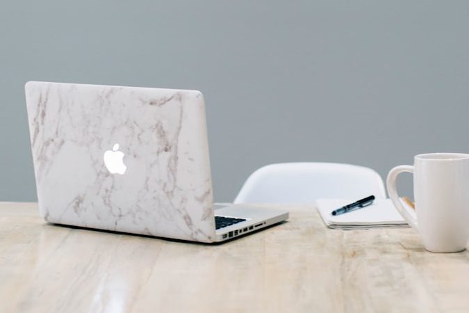 MacBook on table near mug
